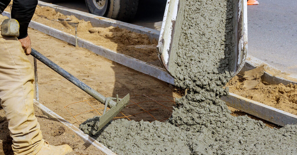 Concrete worker at construction site next to a truck, showcasing adapting concrete mixes technique.