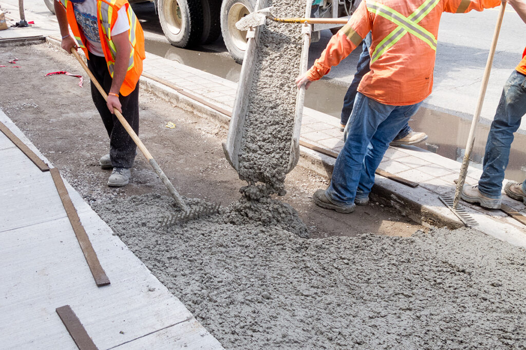 Concrete contractor pouring cement for a sidewalk upgrade.