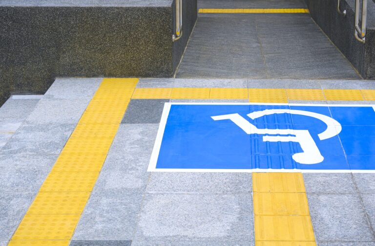 Disabled wheelchair sign with ramp and yellow tactile paving line on different level marble pavement