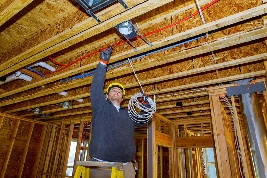 Electrical Contractor working on electrical wire installation in a new house construction site.