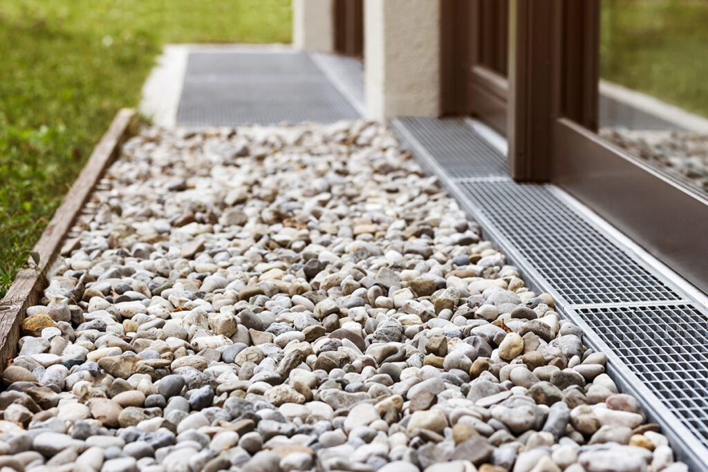 French Drain System: Water Stones by House Wall and Windows