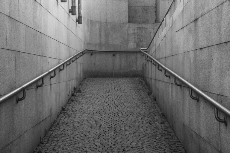 Greyscale shot of a wheelchair ramp by a building captured during the daytime