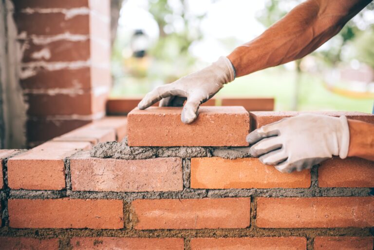 professional construction worker laying bricks and building barbecue in industrial site