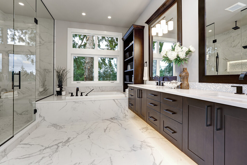 Luxury modern bathroom with dark hardwood cabinets, white tub, and glass door shower.