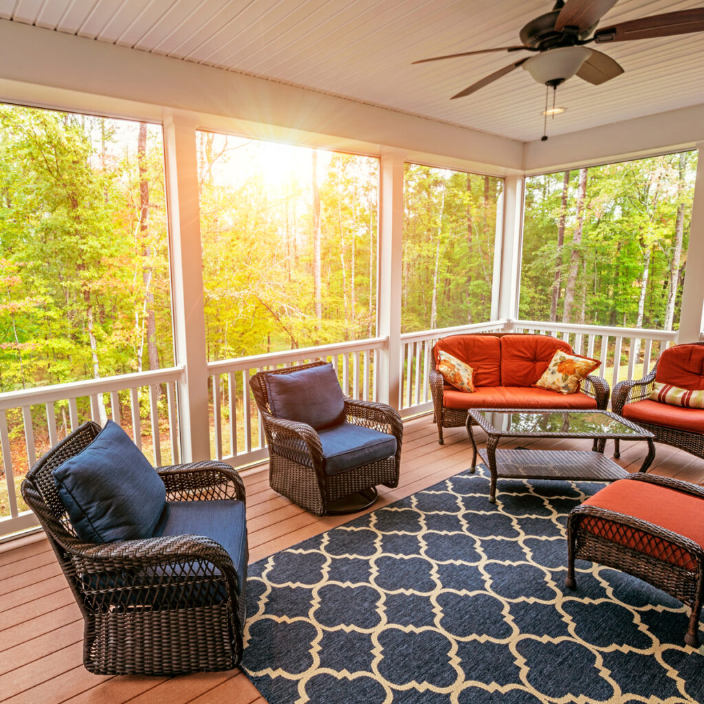 Sunroom Addition Northern Virginia with wicker furniture and forest backdrop.